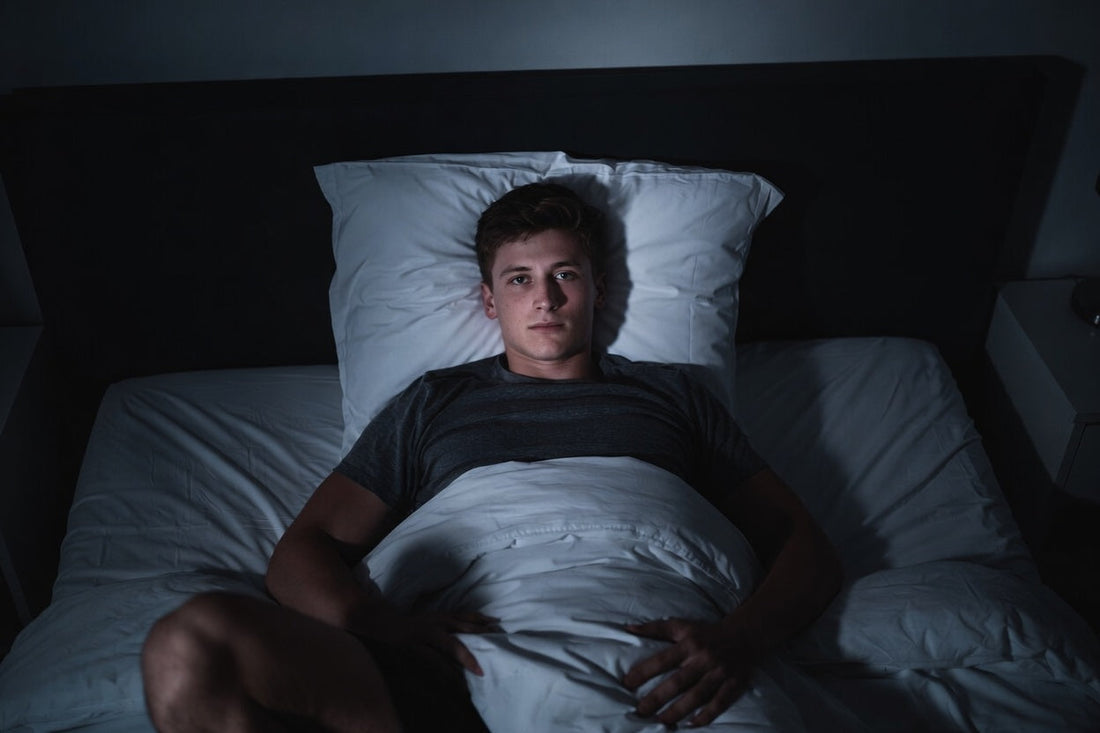athlete lying awake in bed showing how stimulants can disrupt sleep and recovery